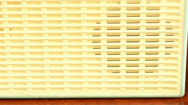 Vintage ivory plastic speaker grille texture of a retro radio