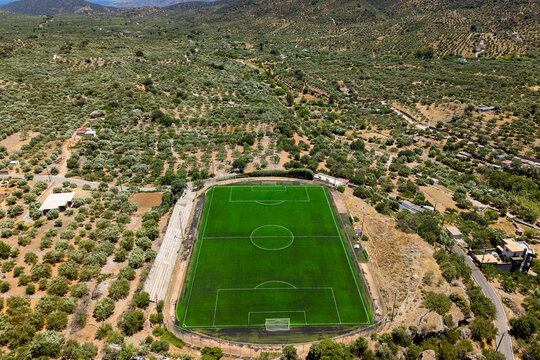 Aerial shot of artificial turf football field set in a dry Mediterranean landscape