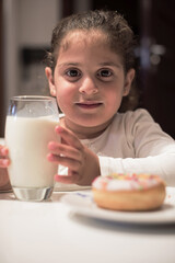 Obraz premium Young girl enjoying milk and a donut at a modern family iftar dinner during Ramadan Eid celebration