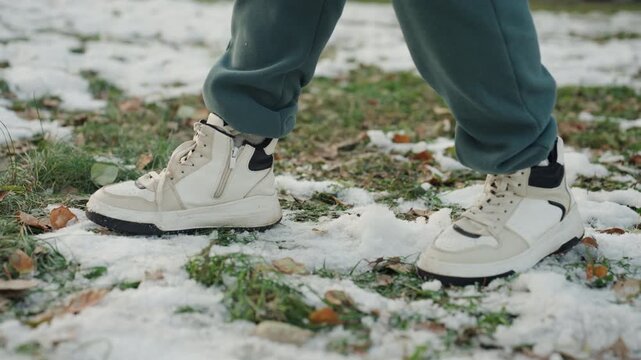 Lowangle boots on slushy snow with quick strides, urgent escape vibe as snatcher moves across park path, laces scuffing through puddles, droplets and melting frost underline cold tension and chase