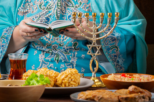 A Jewish woman prays from the siddur at a table