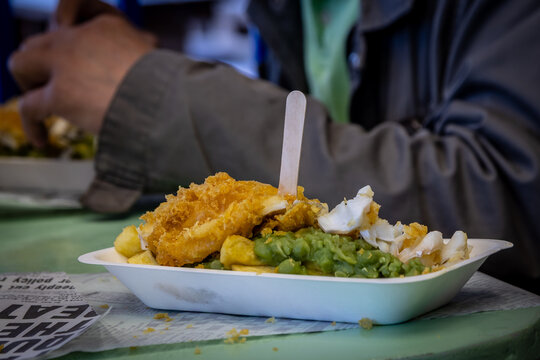 Fish, chips and mushy peas ready to be eaten, with a shallow depth of field