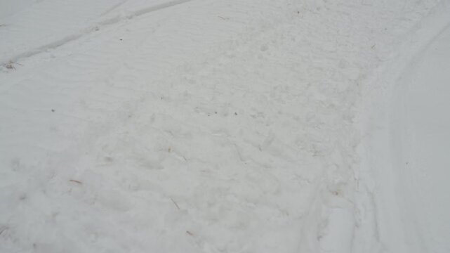Atv tracks in fresh snow, closeup revealing deep tire tread and compacted rut, sequence shows rider carving turn, accelerating through powder, leaving crisp imprint along remote winter trail, mood raw