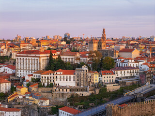 Obraz premium Drone view of Porto skyline in Portugal with Clerigos Tower, red rooftops, historic buildings, and soft dawn light over the city