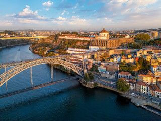 Obraz premium Drone view of Mosteiro da Serra do Pilar in Vila Nova de Gaia near Porto, Portugal, with a tram on Dom Luis I Bridge at sunset