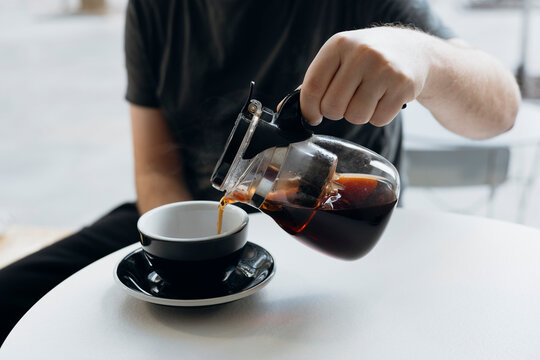 Close up of pouring pu erh tea into cup from glass teapot.
