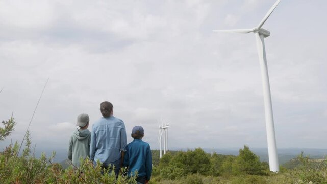Father teaching sons about renewable energy and wind turbines. Parent explaining wind power generation, sustainability, and environmental concepts to his children