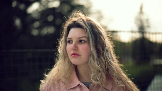 Young woman posing in soft spring light outdoors, natural beauty portrait, lifestyle video in Czech Republic, Europe, commercial use
Young woman with curly hair looking at camera outdoors, natural lig