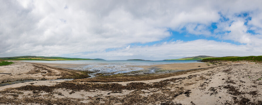 Vue panoramique d'une baie de Loch dans les Orcades, vue depuis une plage de sable, ciel bleu avec quelques nuages, Ecosse