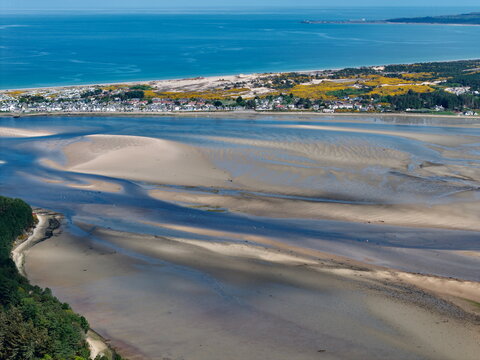 Aerial view of Findhorn Bay featuring intricate sandbars, the coastal village, and the blue waters of the Moray Firth in Findhorn, Scotland, United Kingdom.
