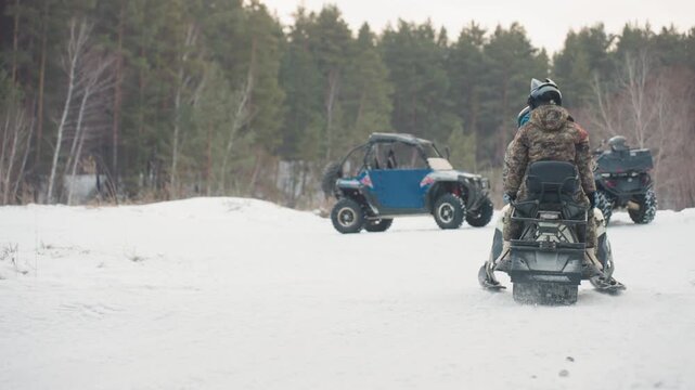 Convoy assembles in snowcovered forest clearing. Snowmobile and utv team congregates in wintry woodland space. Group of riders with snow vehicles assemble in snowy clearing surrounded by pine trees