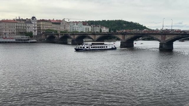 River cruise boat passing under historic bridge in Prague  