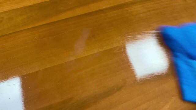 Cleaning Wood Floor: Close-up shot capturing a person&rsquo;s hand using cleaning products on a wooden floor, evoking the sense of freshness and maintenance.