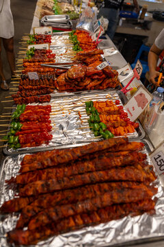 bustling night market in Bangkok, colorful street food stalls serving sizzling skewers, people enjoying authentic Thai cuisine