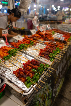 bustling night market in Bangkok, colorful street food stalls serving sizzling skewers, people enjoying authentic Thai cuisine