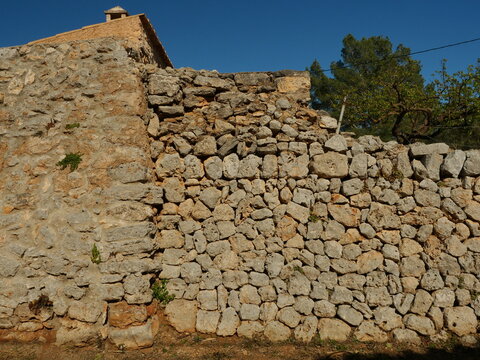Dry stone wall made of mares natural stone in Mallorca. Detailed texture with warm tones and natural light.