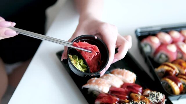 Detailed close up view of ginger and wasabi served in a black plastic sushi delivery container with fresh texture and authentic Japanese food presentation.