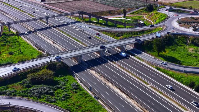 Wide angle shot of multiple road levels and bridges forming a traffic junction in a rural area. Oblique aerial view of complex highway interchange system.