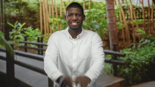 Man in a white shirt with hands pressed together in prayer on a wooden walkway in a forest; prayer hope faith devotion.