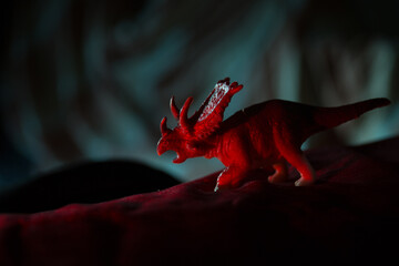 Plastic toy Dinosaur standing on a red carpet © VectorDot