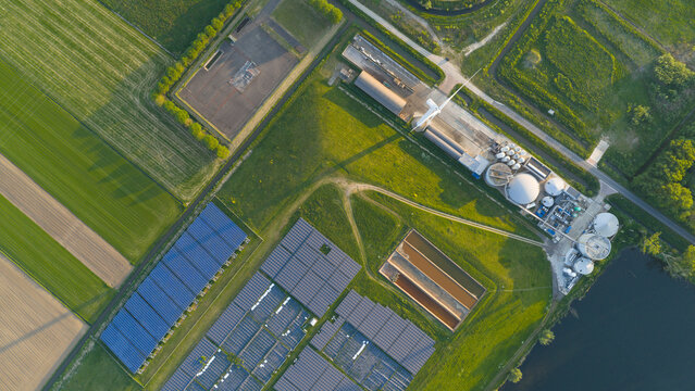 Aerial view of Wabico BV facility featuring solar panel arrays, a wind turbine, and industrial tanks surrounded by green agricultural fields in Waalwijk, Noord-Brabant, Netherlands.
