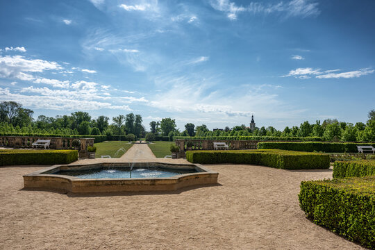 Beautiful baroque formal garden parterre at Milotice castle with gravel paths white benches and high green hedges under blue sky wide horizontal view