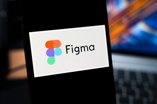 Warsaw, Poland - May 13, 2026: Close-up view of Figma logo displayed on smartphone screen, illustrating the digital design tool in a modern workspace setup with computer in the background
