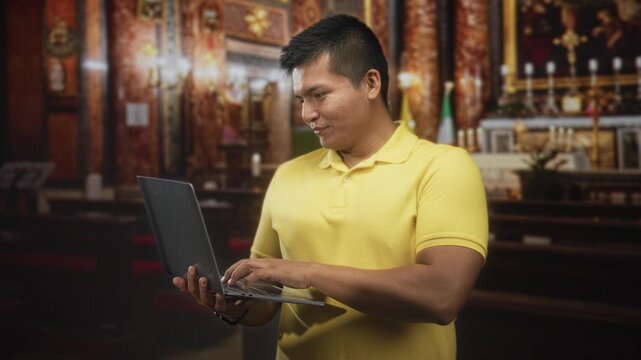 Man in yellow polo typing on laptop with visible hands in ornate church building near altar and candles; contemplation focus.