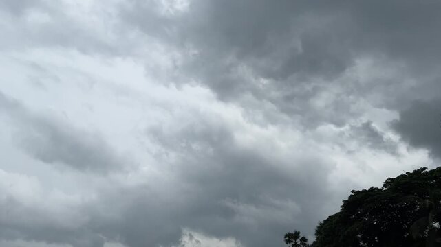 Stormy gray clouds moving quickly across overcast sky as dark rain clouds gather before thunderstorm during day time creating dramatic atmosphere in this high quality video footage clip.