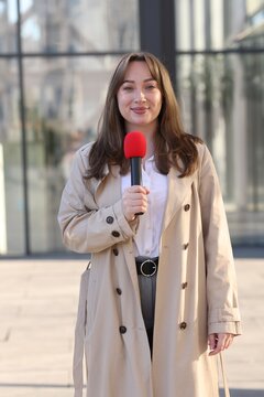 Professional journalist with microphone working on city street