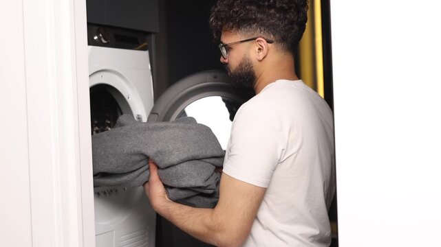 Smiling man doing laundry using washing machine