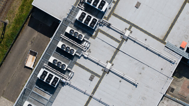 Aerial view of industrial rooftop HVAC units with ventilation fans and complex piping systems on a flat grey roof Utrecht, Utrecht, Netherlands.