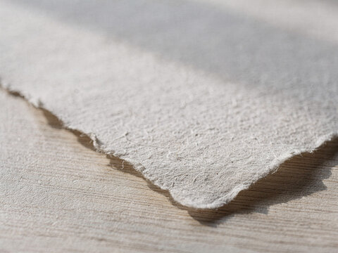 Close-up of handmade paper with deckled edge on wooden surface
