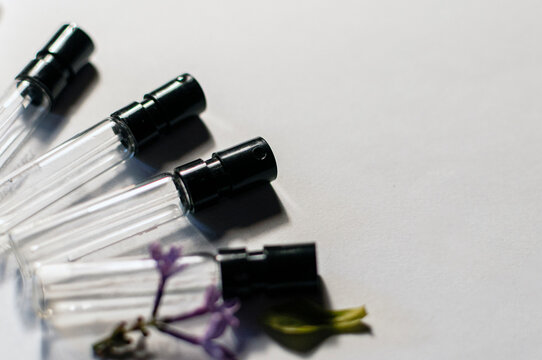 Small glass perfume sample vials with black spray heads on a white background