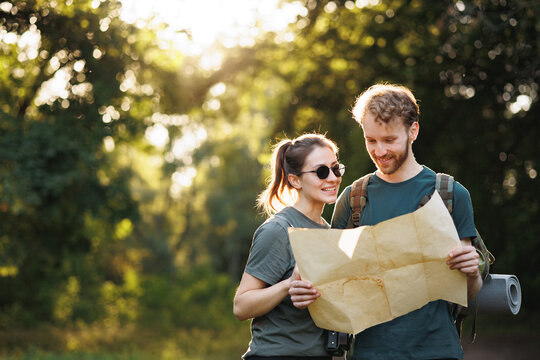 Young couple standing in forest at summer with a map