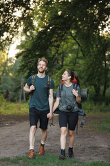 Fototapeta premium Photo of couple standing in forest at summer with a backpack