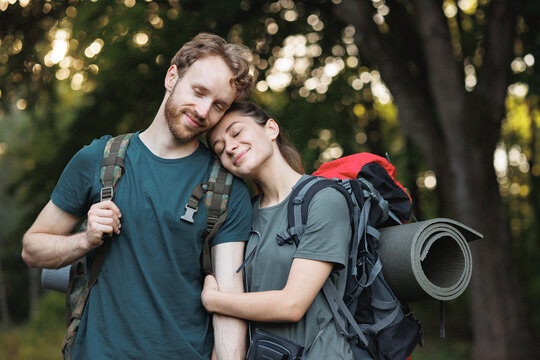 Photo of couple standing in forest at summer with a backpacks