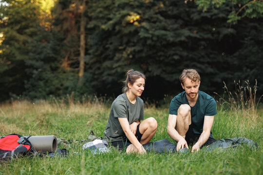 Young couple setting up a tent in forest at summer