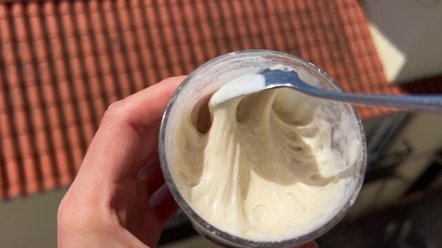 Stirring active sourdough starter with spoon in glass jar