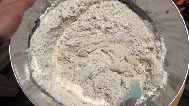 Feeding sourdough starter in stainless steel bowl close 