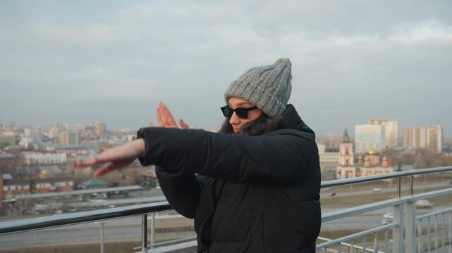 Contemporary rooftop vogue dance with skyline, stylized arm poses and dramatic handlines, knit cap and sunglasses, moody sky and city vista, intimate closeups and confident performance for camera