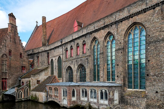 Historic brick building with arched windows along a canal  Bruges