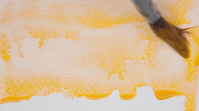 Close up of orange watercolour drawing paints on paper. Artist draws with a brush, liquid analog effects for background with copy space for text in center. 