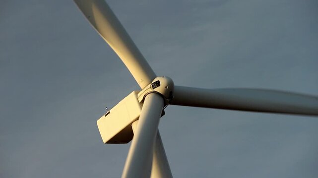 A wind turbine spins as the morning sun shines on it.