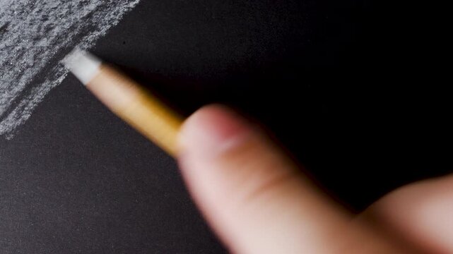 close up of chalk pencil drawing on textured black paper. slow motion footage. Background video can be used as overlay. doodling hatching