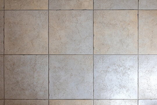 Close-up of beige ceramic floor tiles with grout lines