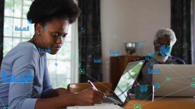 Woman writing notes while senior man typing, data nodes appearing linking laptops for tech work