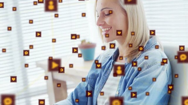 Seated woman typing laptop causing heart or comment or play icons floating past face, boosting marke