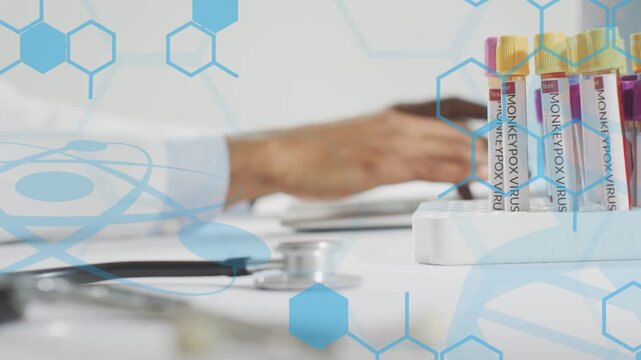 Male doc typing on keyboard and logging monkeypox tubes, stethoscope near, blue hexagons overlaying