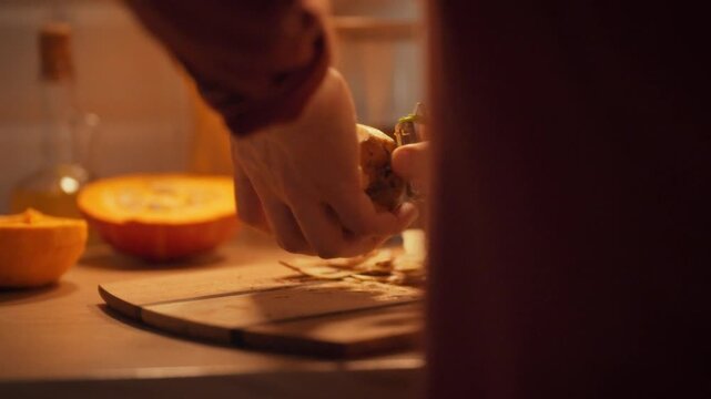 In a cozy evening kitchen, a male cook skillfully peels potatoes with a specialized vegetable peeler, illustrating a key step in home food preparation and the comforting rhythm of cooking